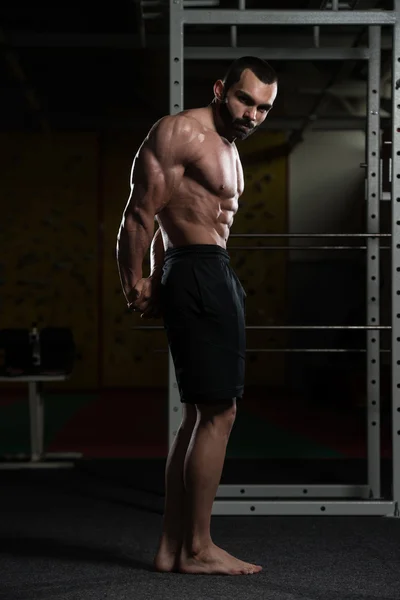 Homem muscular flexionando músculos no ginásio — Fotografia de Stock