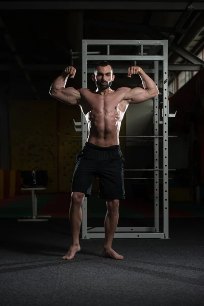 Bodybuilder presterende voorzijde dubbele biceps vormen — Stockfoto