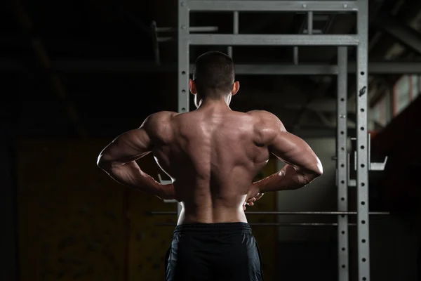 Bodybuilder effectuant la posture de propagation latérale arrière — Photo