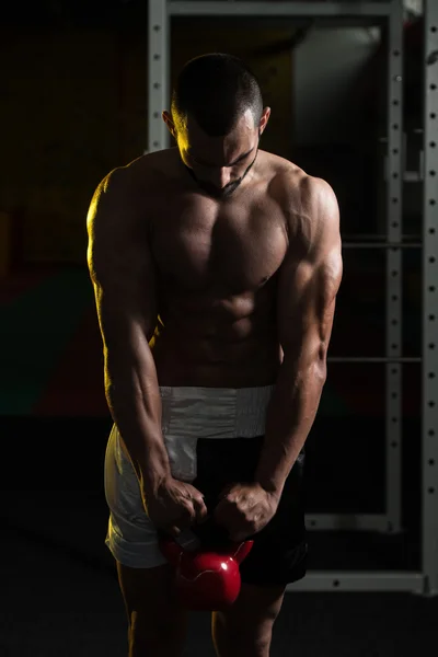 Homem de fitness usando Kettlebells dentro do ginásio — Fotografia de Stock