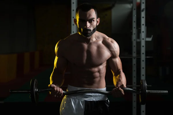 Homem muscular exercitando bíceps com barra — Fotografia de Stock