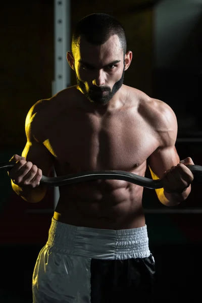 Homem muscular exercitando bíceps com barra — Fotografia de Stock