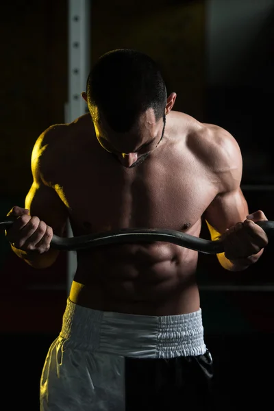 Hombre en el gimnasio ejercitando bíceps con barra — Foto de Stock