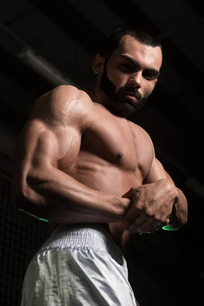 Musculoso hombre flexionando los músculos en el gimnasio — Foto de Stock