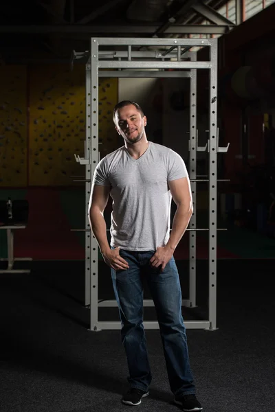 Człowiek w dżinsy, stojąc w ciemnej sali gimnastycznej — Zdjęcie stockowe