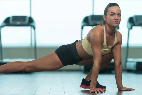 Unga Fitness kvinna sträckor på golvet — Stockfoto