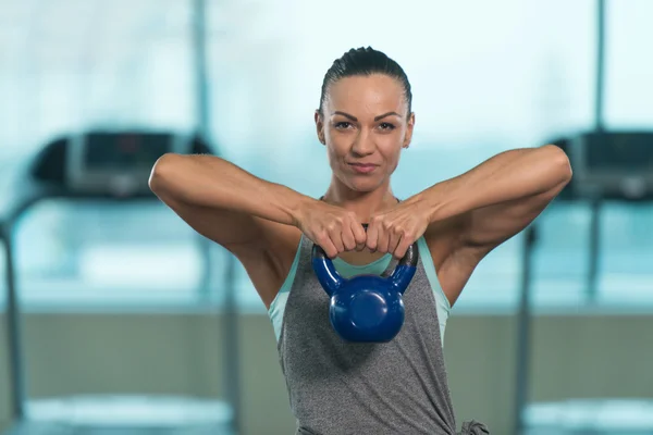 Женщина делает тяжелые упражнения веса с чайник-колокольчик — стоковое фото