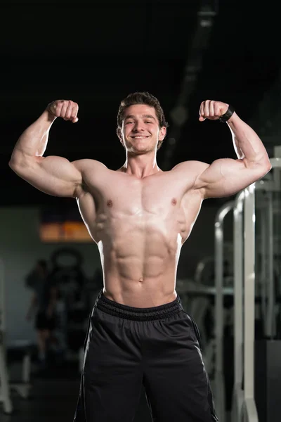 Culturista realizando frente doble bíceps Pose en el gimnasio — Foto de Stock