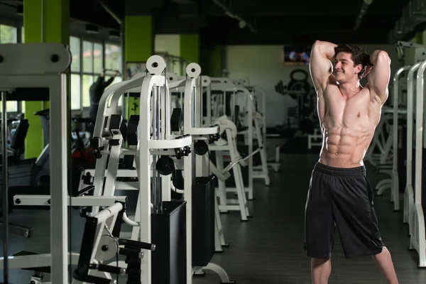 Homem muscular flexionando músculos no ginásio — Fotografia de Stock