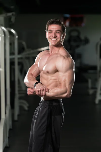 Jeune bodybuilder flexion des muscles Pose poitrine latérale — Photo
