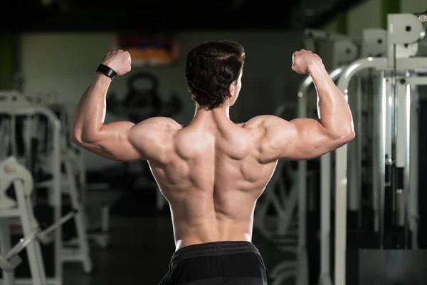Joven culturista Flexing trasero doble bíceps Pose —  Fotos de Stock