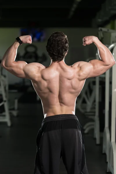 Muscular hombre flexión músculos trasero doble bíceps Pose —  Fotos de Stock