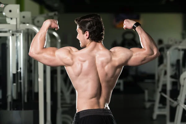 Junge Bodybuilderin biegt hinteren doppelten Bizeps — Stockfoto