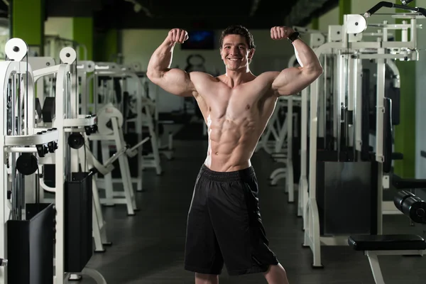 Fisiculturista Flexing frente duplo bíceps dose no ginásio — Fotografia de Stock