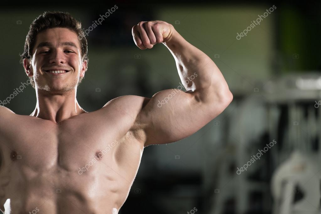 Bodybuilder Flexing Front Double Biceps Pose In Gym - Stock Photo. 