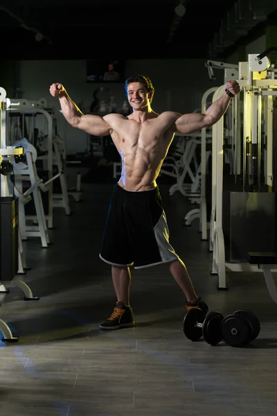 Uomo muscolare che flette i muscoli in palestra — Foto Stock