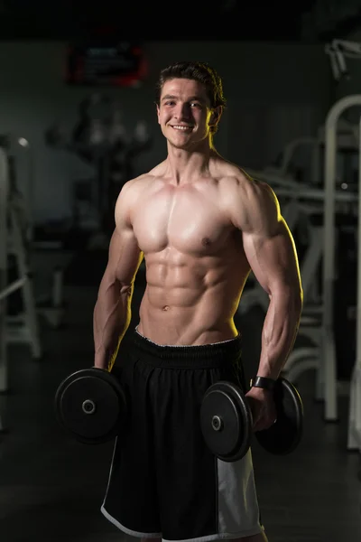 Mladý muž s činkami cvičení Biceps — Stock fotografie