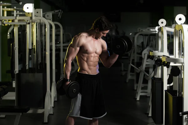 Jeune homme avec haltères exercice Biceps — Photo