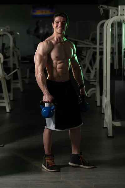 Homem de fitness usando Kettlebells dentro do ginásio — Fotografia de Stock