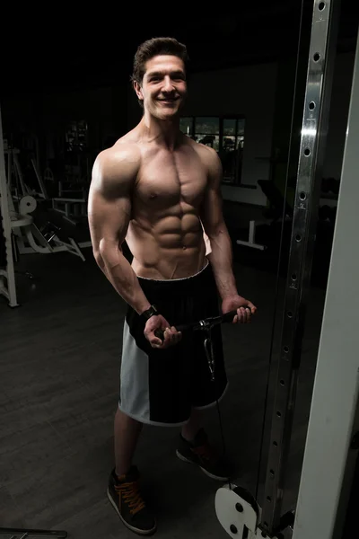 Potężny muskularny mężczyzna wykonując Biceps na kabel maszyny — Zdjęcie stockowe