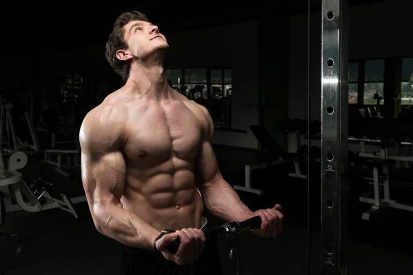 Potente hombre muscular ejercitando bíceps en la máquina de cable — Foto de Stock