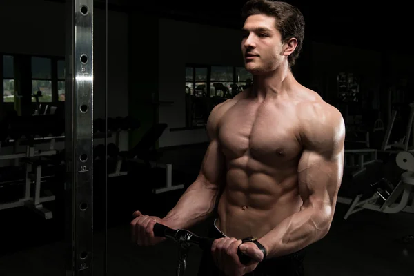 Hombre muscular ejercitando bíceps en la máquina de cable —  Fotos de Stock