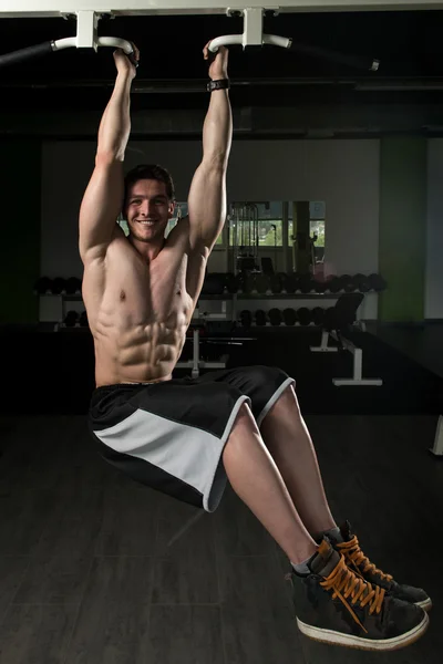 Joven hombre realizando colgante pierna plantea ejercicio —  Fotos de Stock