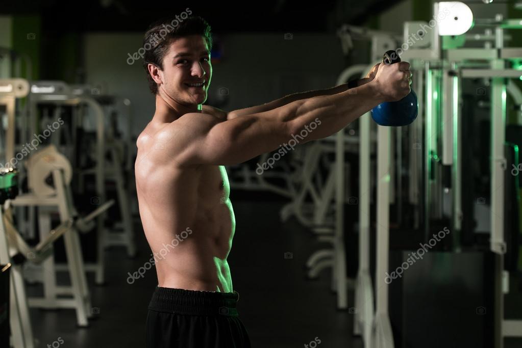 Fitness Man Using Kettlebells Inside Gym — Stock Photo © ibrak 114342954