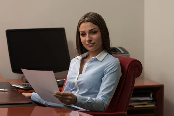 Młoda kobieta w biurze patrząc na papier — Zdjęcie stockowe