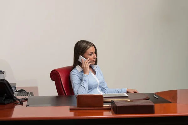 Ung kvinna med mobiltelefon på kontoret — Stockfoto