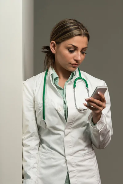 Ritratto di medico femminile utilizzando il suo telefono cellulare — Foto Stock