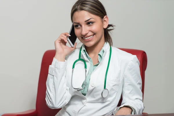 Vriendelijke vrouw dokter praten op mobiele telefoon — Stockfoto