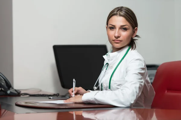 Arzt sitzt am Schreibtisch und unterschreibt einen Vertrag — Stockfoto