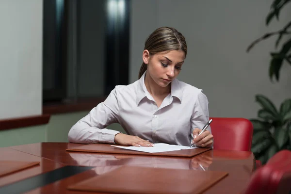 Geschäftsfrau sitzt am Schreibtisch und unterschreibt einen Vertrag — Stockfoto