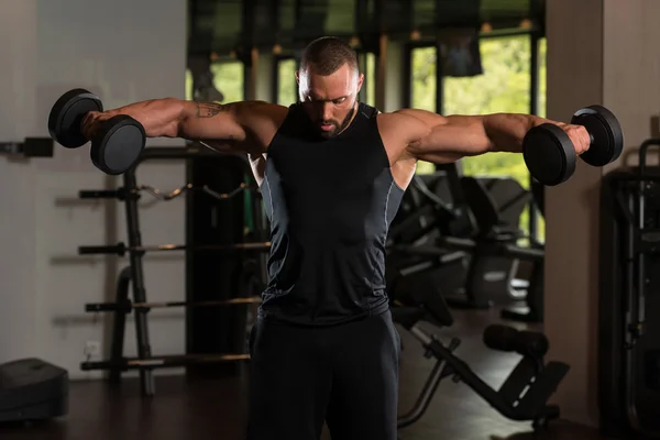 Muscled manlig modell tränar axlar med hantlar — Stockfoto