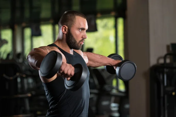 Bodybuilder oefening schouders met halters — Stockfoto