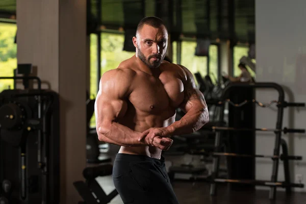 Fitness geformter Muskelmann posiert in dunkler Turnhalle — Stockfoto