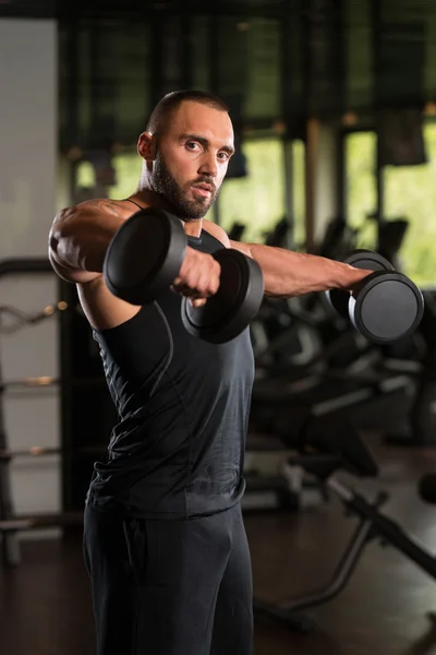 Muscoloso maschio modello esercizio spalle con manubri — Foto Stock