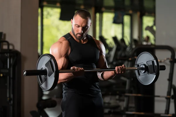 Muskulöses männliches Modell, das Bizeps mit Langhantel trainiert — Stockfoto