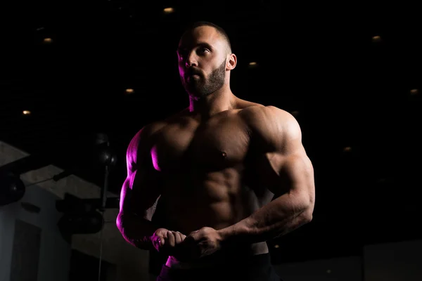 Fitness en forma de hombre muscular posando en el gimnasio oscuro — Foto de Stock