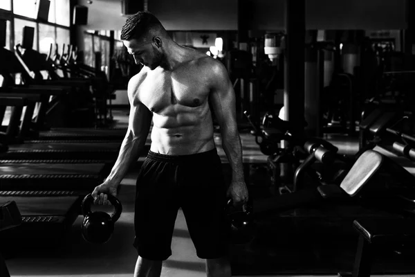 Homem de fitness usando Kettlebells dentro do ginásio — Fotografia de Stock