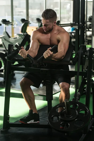 Unga Bodybuilder gör övning för Biceps på maskin — Stockfoto