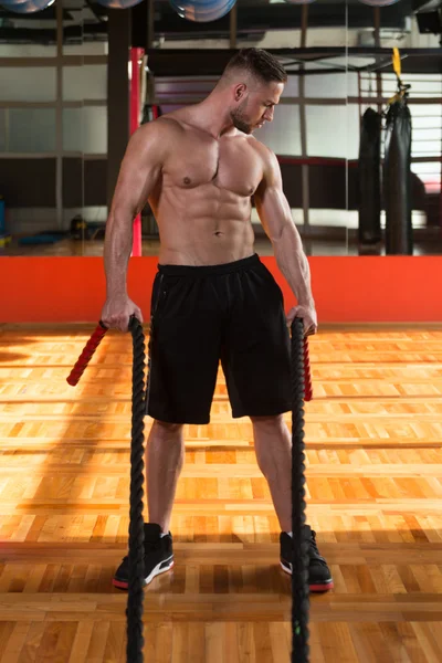 Joven hombre luchando cuerdas en el ejercicio de entrenamiento de gimnasio — Foto de Stock