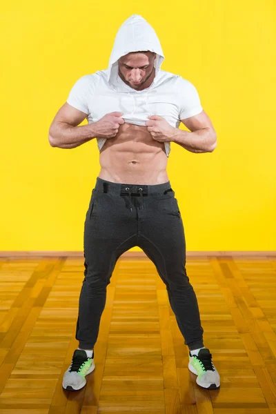 Молодой культурист разминает мышцы на жёлтом фоне — стоковое фото