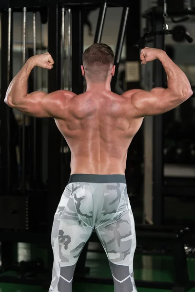 Musculoso hombre flexionando los músculos en el gimnasio — Foto de Stock