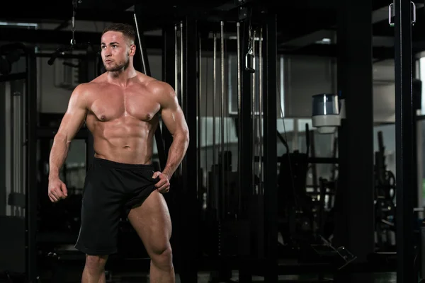 Fitness en forma de hombre muscular posando en el gimnasio oscuro —  Fotos de Stock