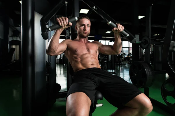 在健身房里锻炼胸部在机器上的男人 — 图库照片