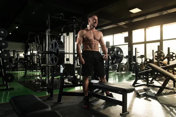 Musculoso hombre flexionando los músculos en el gimnasio —  Fotos de Stock