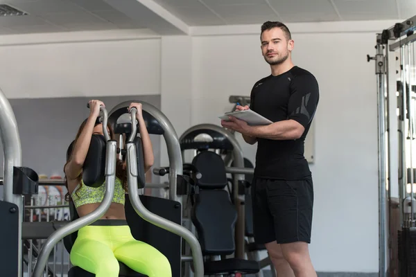 Donna treno petto su macchina con personal trainer — Foto Stock