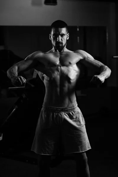 Homem muscular flexionando músculos no ginásio — Fotografia de Stock